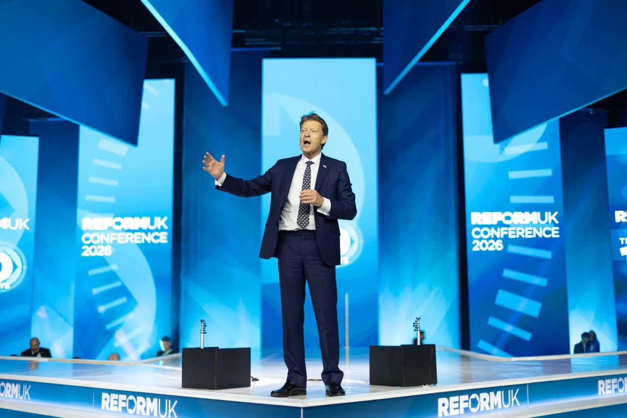 Richard Tice delivers his Reform UK Conference 2026 keynote on stage in Birmingham, gesturing beneath REFORMUK CONFERENCE 2026 branding.
